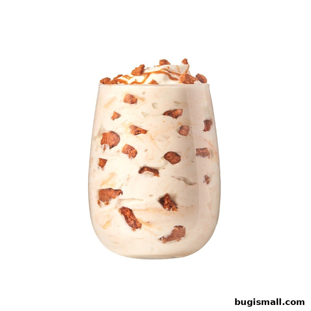 A creamy dessert with cookie crumbles and caramel drizzle in a clear glass.