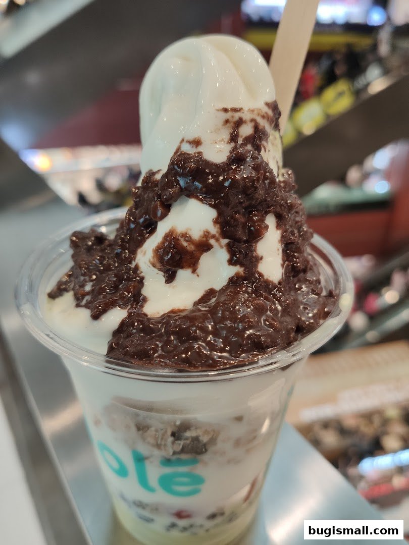 A close-up of a delicious frozen yogurt dessert with chocolate toppings in a clear cup.