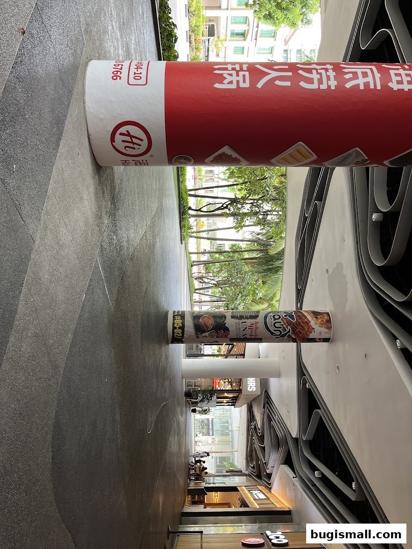 A view down a modern shopping mall corridor with shops and decorative pillars.