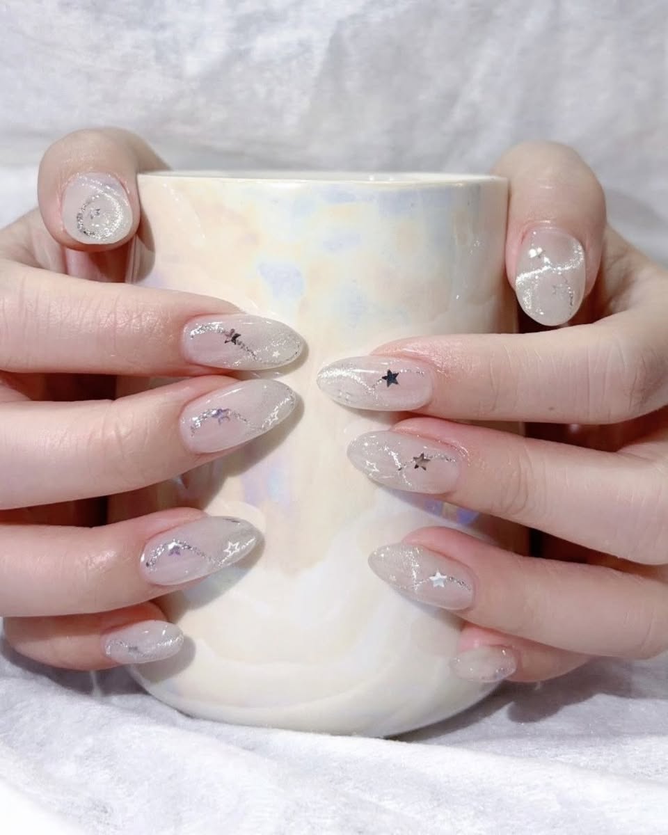 Nail design with sheer pink polish and silver star accents